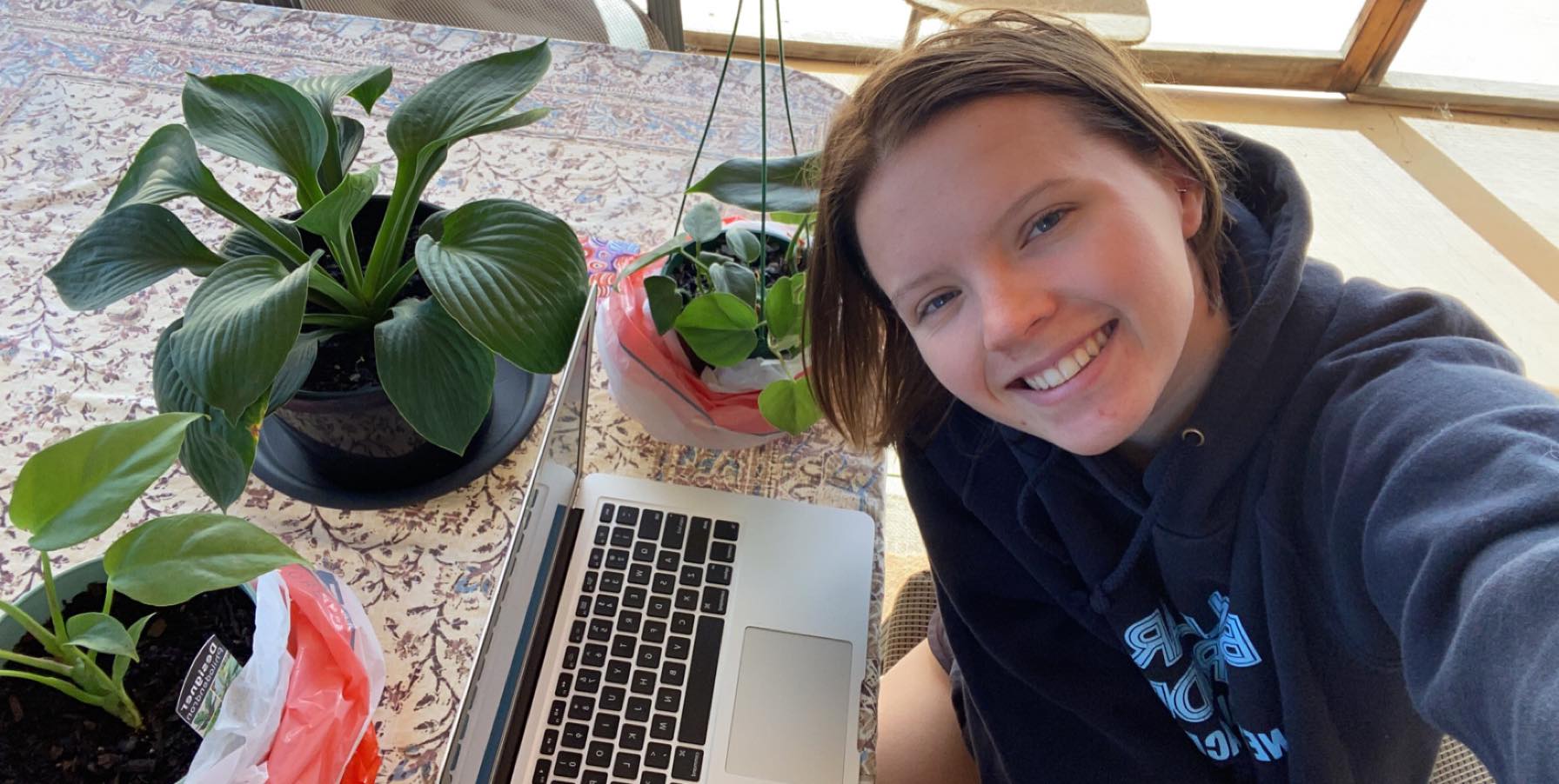 Julia taking a selfie in front of computer with plants.