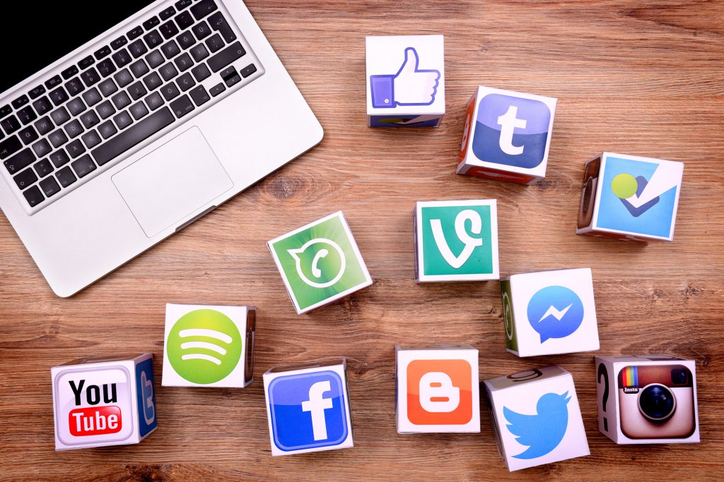 Social media brands on blocks on a table near laptop.